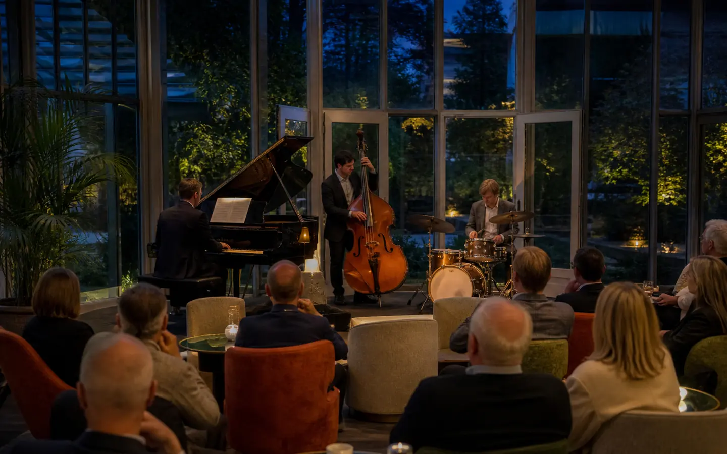 Jazztrio speelt voor gasten in een glazen tuinsalon