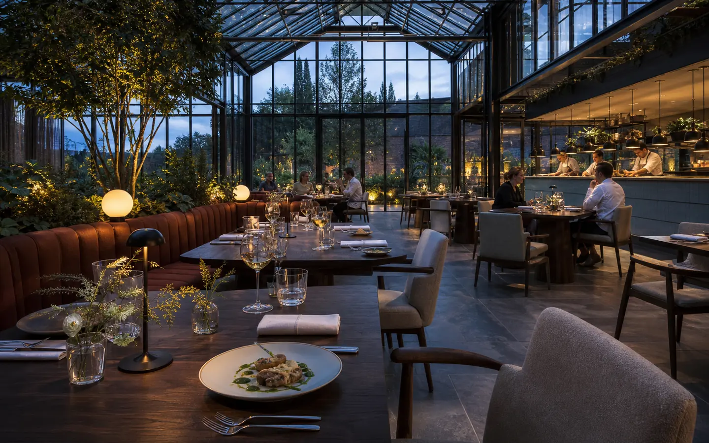 Restaurant onder een glazen dak met open keuken en tuinbeplanting