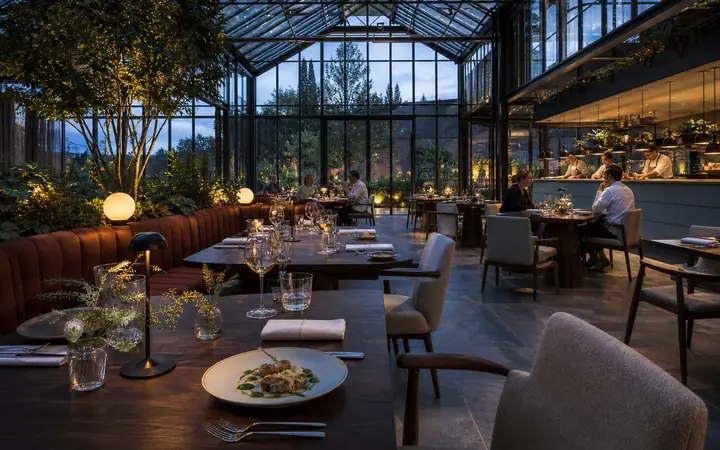 Lichte restaurantserre met gedekte tafels en uitzicht op de tuin